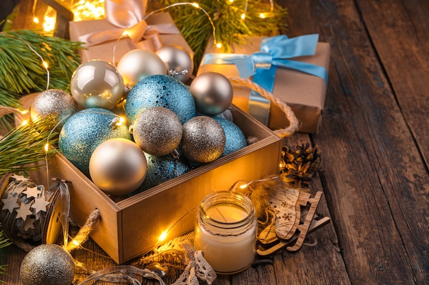 Una caja con bolas de Navidad doradas y azules en ramas de árboles de Navidad con luces brillantes. El concepto de Navidad y año nuevo.