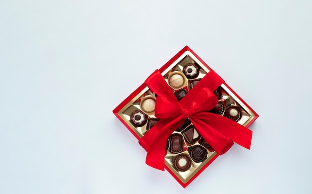 Foto caja de bombones de chocolate con lazo rojo sobre celeste