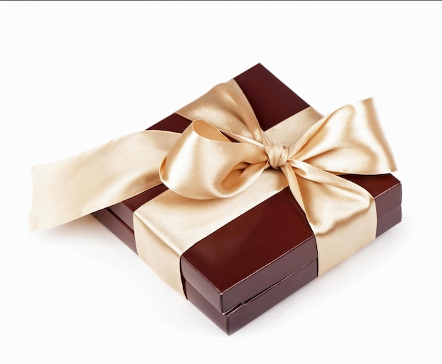 Foto caja con caramelos y cinta dorada sobre el blanco.