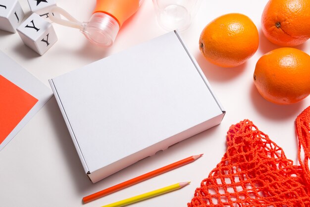 Caja de cartón en blanco con naranjas frescas, endecha plana