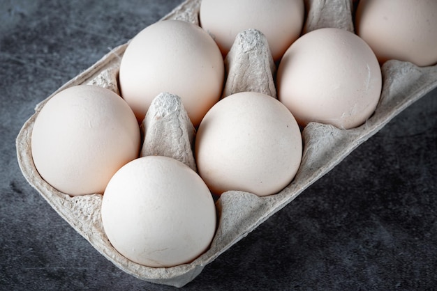 Caja de cartón con huevos en mesa gris