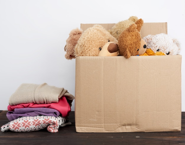 Caja de cartón marrón llena de cosas y juguetes para niños.