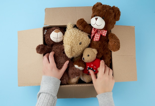 Foto caja de cartón marrón con varios ositos de peluche.