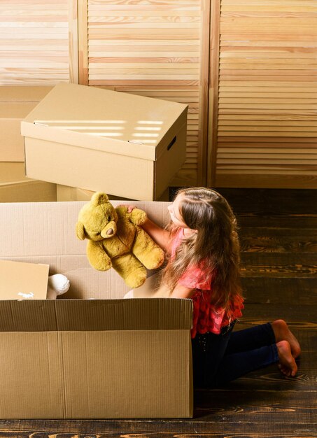 Caja de cartón de niño feliz. reparación de habitación. nuevo apartamento. desembalaje de cajas de mudanza. Cajas de cartón: mudarse a una nueva casa. niña feliz sentada en la habitación en cajas. compra de vivienda nueva. mis juguetes.