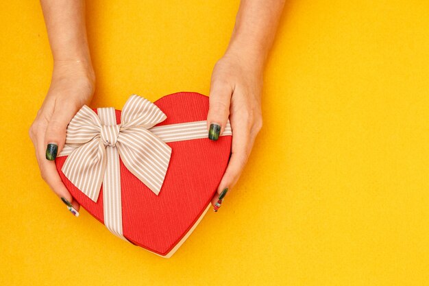 Caja de cartón de regalo biodegradable en forma de corazón en manos de mujeres