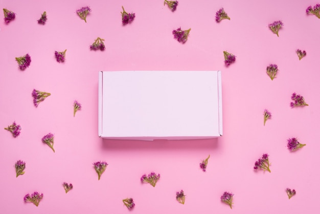 Caja de cartón rosa sobre fondo de color decorado con flores frescas