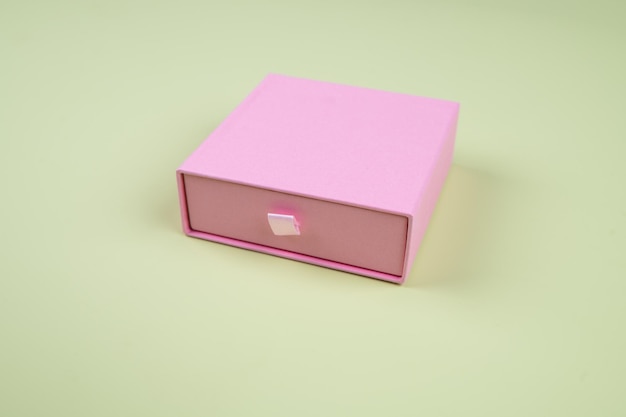 Caja de cartón rosa sobre fondo verde pastel, vista lateral. foto de alta calidad