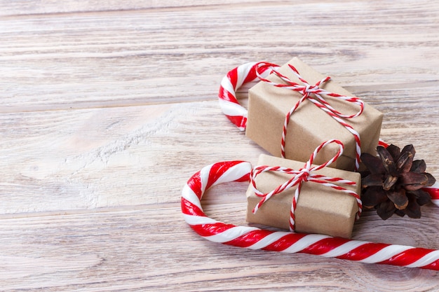 Caja casera con un lazo rojo cerca de bastones de caramelo de Navidad