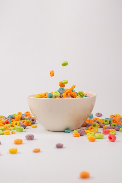 Caja de cereales de colores para el desayuno de la mañana. Copos de maíz cayendo al tazón blanco. Movimiento. Espacio de copia.