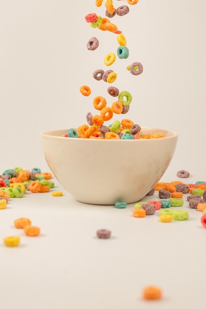 Caja de cereales de colores para el desayuno de la mañana. Copos de maíz cayendo al tazón blanco. Movimiento. Espacio de copia.