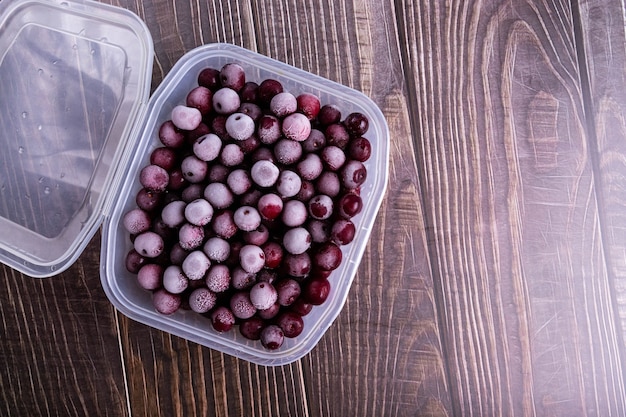 Caja con cerezas maduras congeladas en una mesa de madera