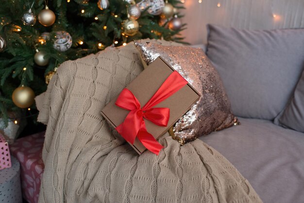 Una caja con una cinta roja, un regalo se encuentra debajo del árbol de Navidad.