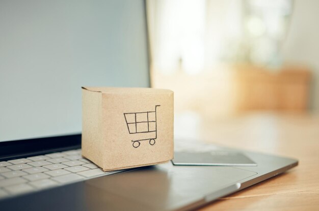 Caja de compras en línea y computadora portátil con tarjeta de crédito para el pago de la compra de productos o bienes de servicio Logotipo del carro de cartón Fintech y tarjeta bancaria financiera para el mercado minorista cibernético de comercio electrónico y ventas