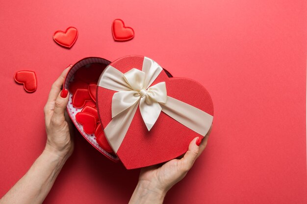 Caja de corazón de San Valentín en manos de mujer en rojo