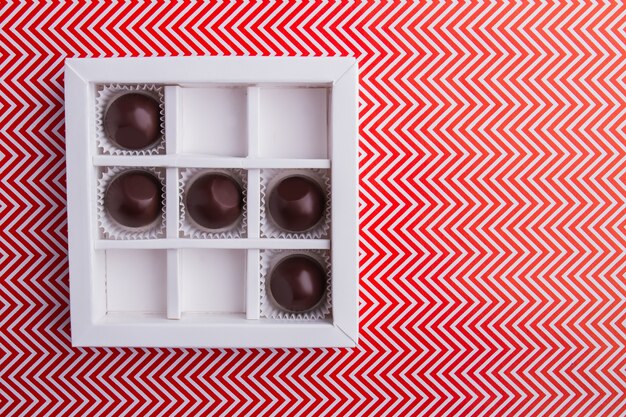 Caja cuadrada blanca con bombones redondos de chocolate