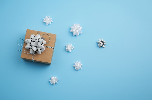 Caja cuadrada marrón con un regalo atado con un lazo azul