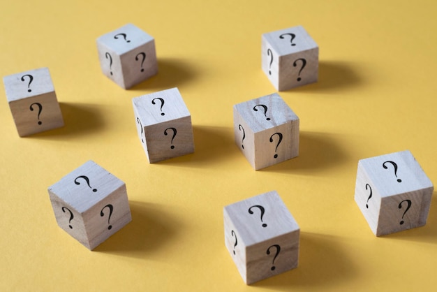 Caja de cubo de madera con signo de interrogación en fondo amarillo