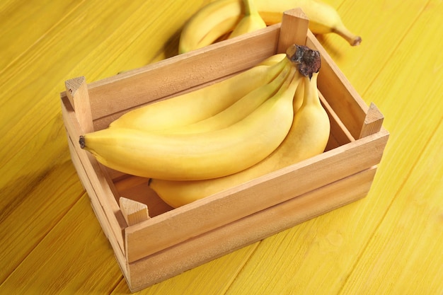 Caja con deliciosos plátanos sobre fondo de madera