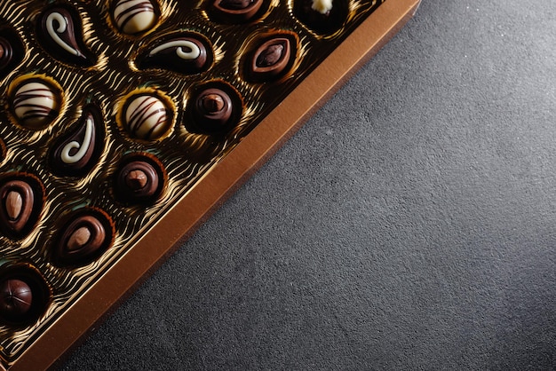Una caja de diferentes chocolates mezcla de surtido de chocolate en el espacio de copia de la vista superior de la mesa negra