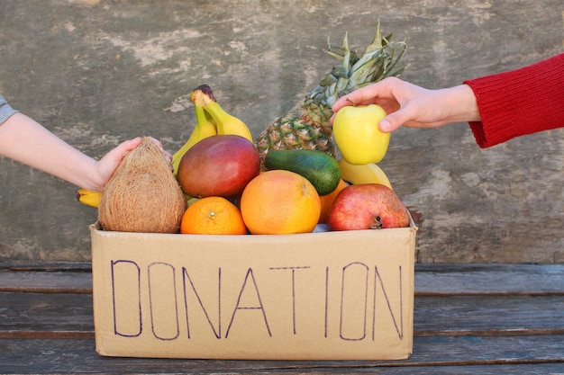 Caja de donación con comida sobre fondo de madera vieja.