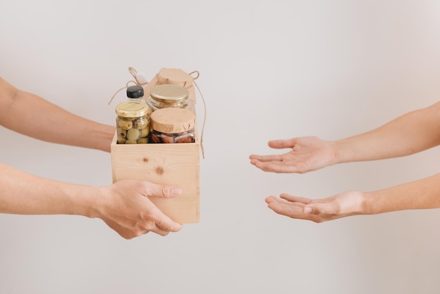 Caja de donación con varios alimentos. Un voluntario pasa una caja de cartón con cereales secos, conservas, huevos, aceite. De mano en mano.