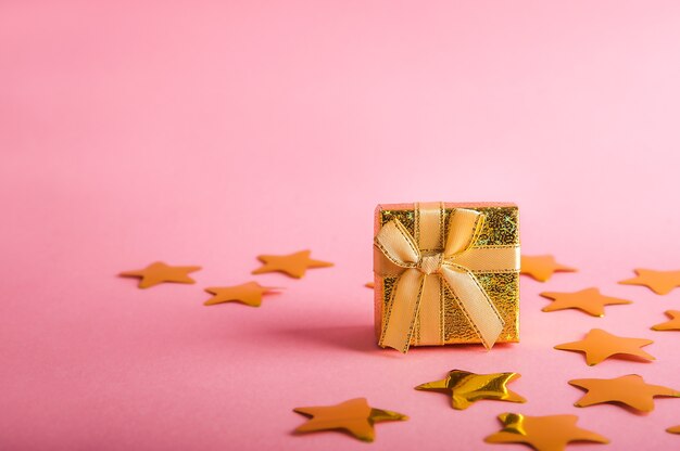 Caja dorada con regalo. Confeti de estrellas doradas.