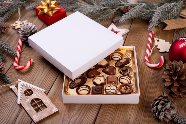 Foto caja de dulces de chocolate navideño sobre una mesa de madera con decoración navideña de temporada