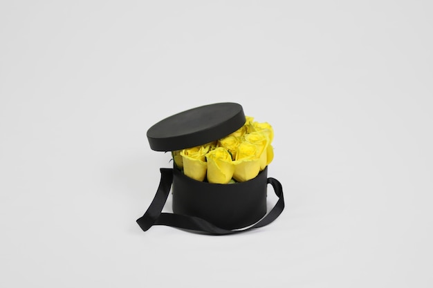 Foto caja de embalaje de flores de regalo redonda negra con rosas amarillas en el interior y tapa abierta
