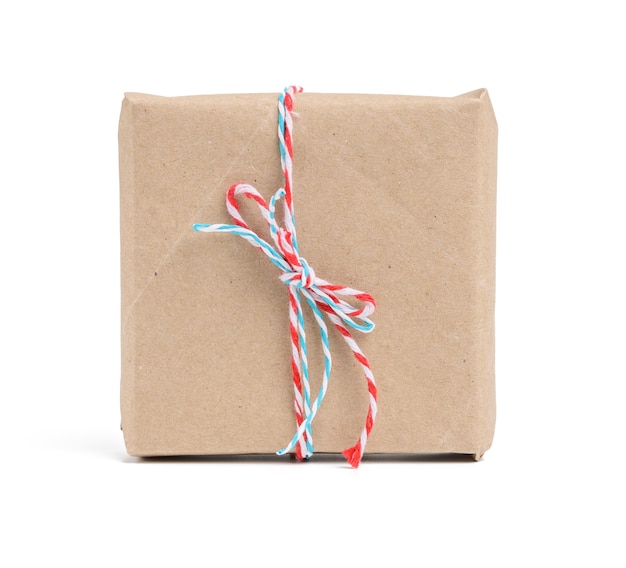 Caja envuelta en papel kraft marrón y atada con cuerda roja, regalo aislado sobre fondo blanco.
