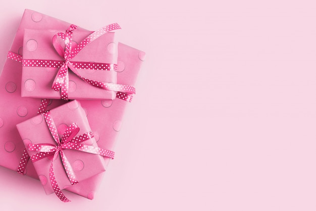 Caja envuelta en papel de regalo rosa y cinta, sobre un fondo rosa