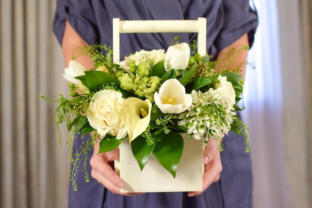 Una caja con flores blancas en manos de una mujer Hermosas flores frescas vacaciones para mujeres Chica con flores