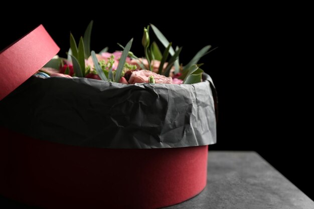 Caja con flores frescas y macarrones sobre fondo negro