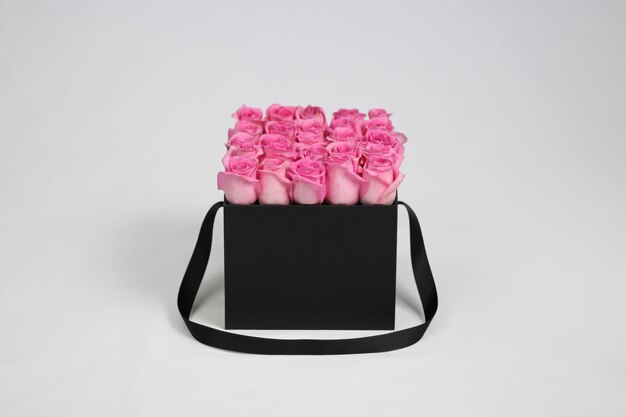 Caja de flores de regalo cuadrada negra con rosas rosadas en el interior