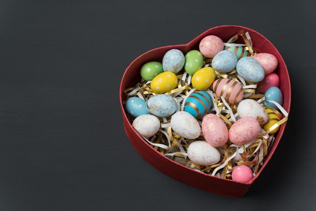 Caja en forma de corazón con brillantes coloridos huevos de Pascua.