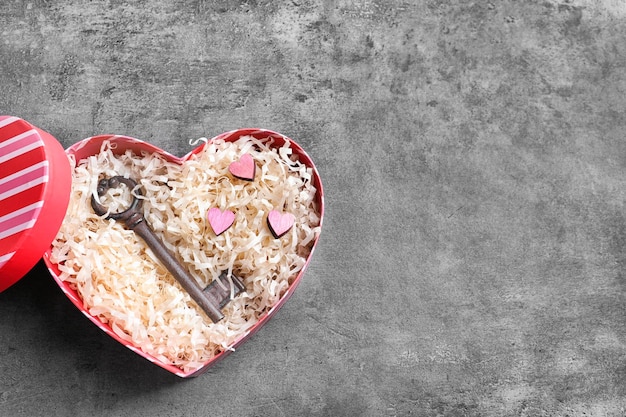 Caja en forma de corazón con llave sobre fondo gris