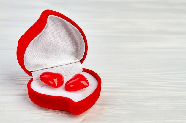 Caja en forma de corazón con pendientes rojos. Caja de regalo de San Valentín con dos accesorios en forma de corazón rojo y copie el espacio.