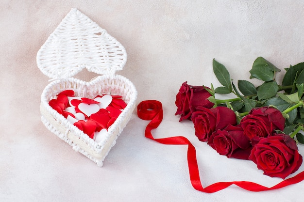 Caja en forma de corazón con ramo de cinco rosas y una cinta de raso roja