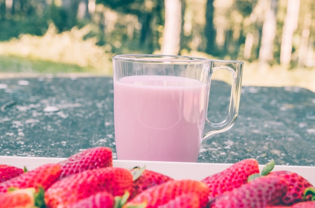 Caja de fresas en una mesa rústica en el campo con un batido de fresa