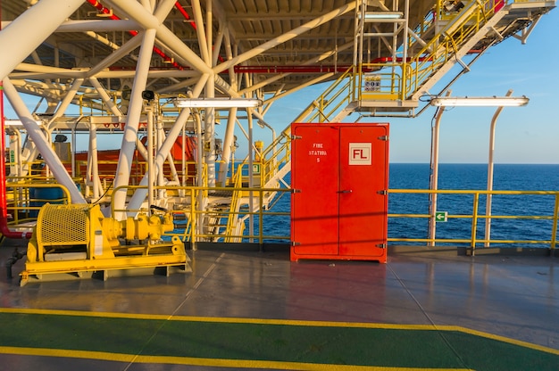 Caja de fuego rojo debajo de la cubierta del helicóptero en la plataforma de perforación costa afuera con el mar azul marino