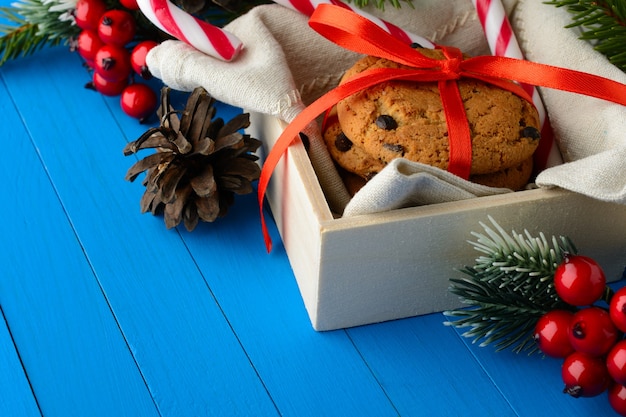 La caja con galletas de chocolate en arreglo con bastones de caramelo y decoración navideña.