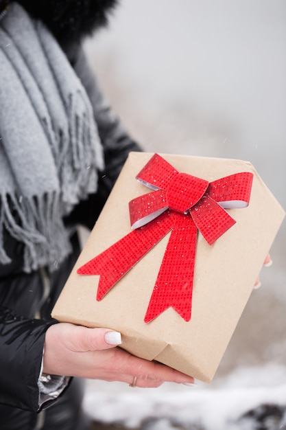 Caja grande con lazo rojo en manos femeninas