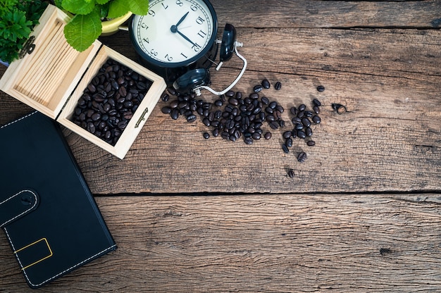 Caja de granos de café, cuaderno, reloj en el escritorio, vista superior