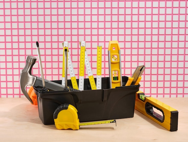 Caja de herramientas de plástico negro con diferentes herramientas de carpintero, herramientas de construcción DIY, cortador de caja de martillo, niveles de construcción y cinta métrica
