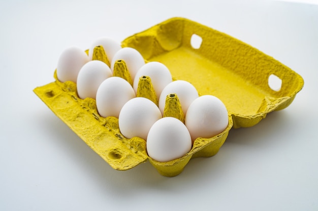 Caja de huevos abierta con diez huevos aislado sobre fondo blanco.