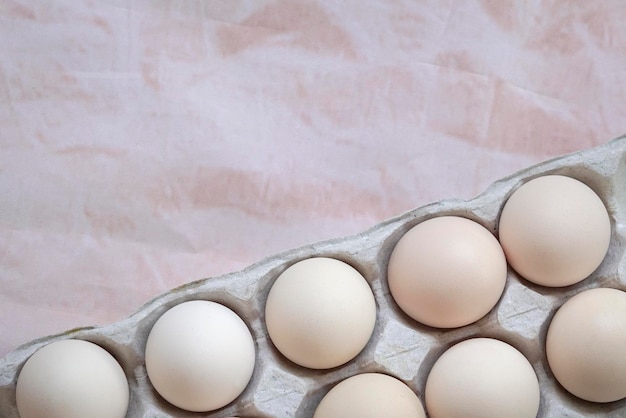 Caja de huevos blancos sobre fondo de color beige