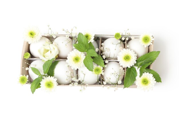 Caja de huevos con huevos y flores aislado sobre fondo blanco.