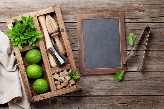 Caja de ingredientes de cóctel Mojito y accesorios de bar en mesa de madera Vista superior con espacio de copia