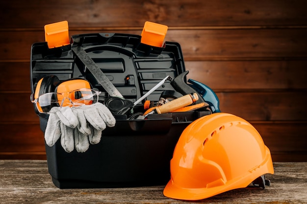 Caja de juego de herramientas de plástico abierta con casco de seguridad para la construcción y varias herramientas de mano.