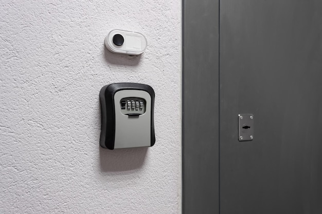 Caja de llaves con cerradura de combinación junto a la puerta y botón de timbre en la pared