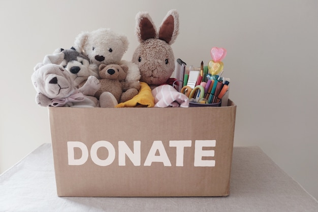 Foto una caja llena de juguetes usados, paños, libros y artículos de papelería para donación.